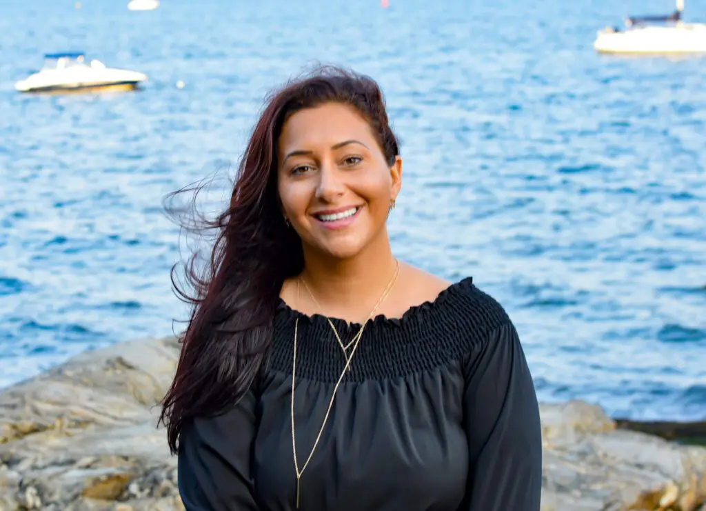 A woman standing on the beach near water.