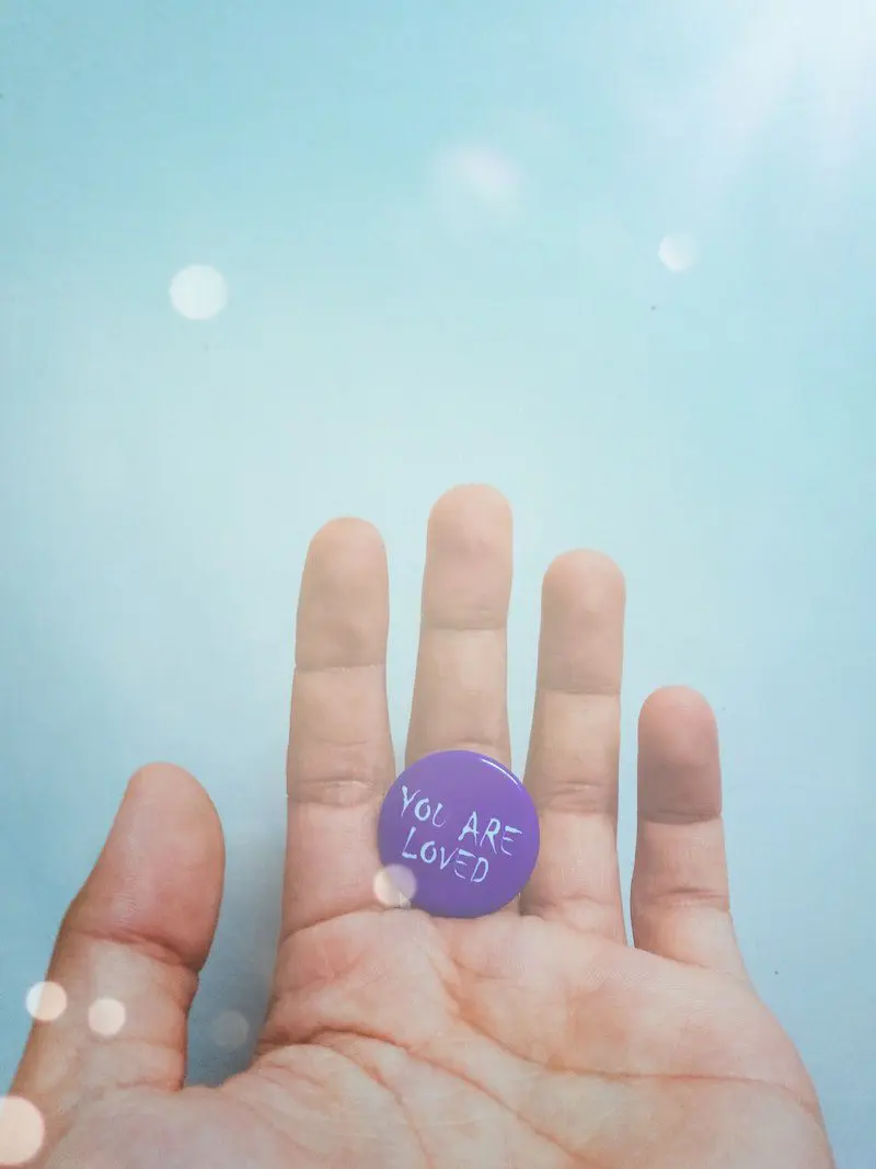 A person holding up their hand with a purple button.