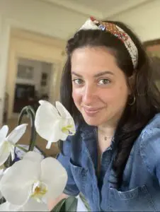 A woman with long hair and headband holding flowers.