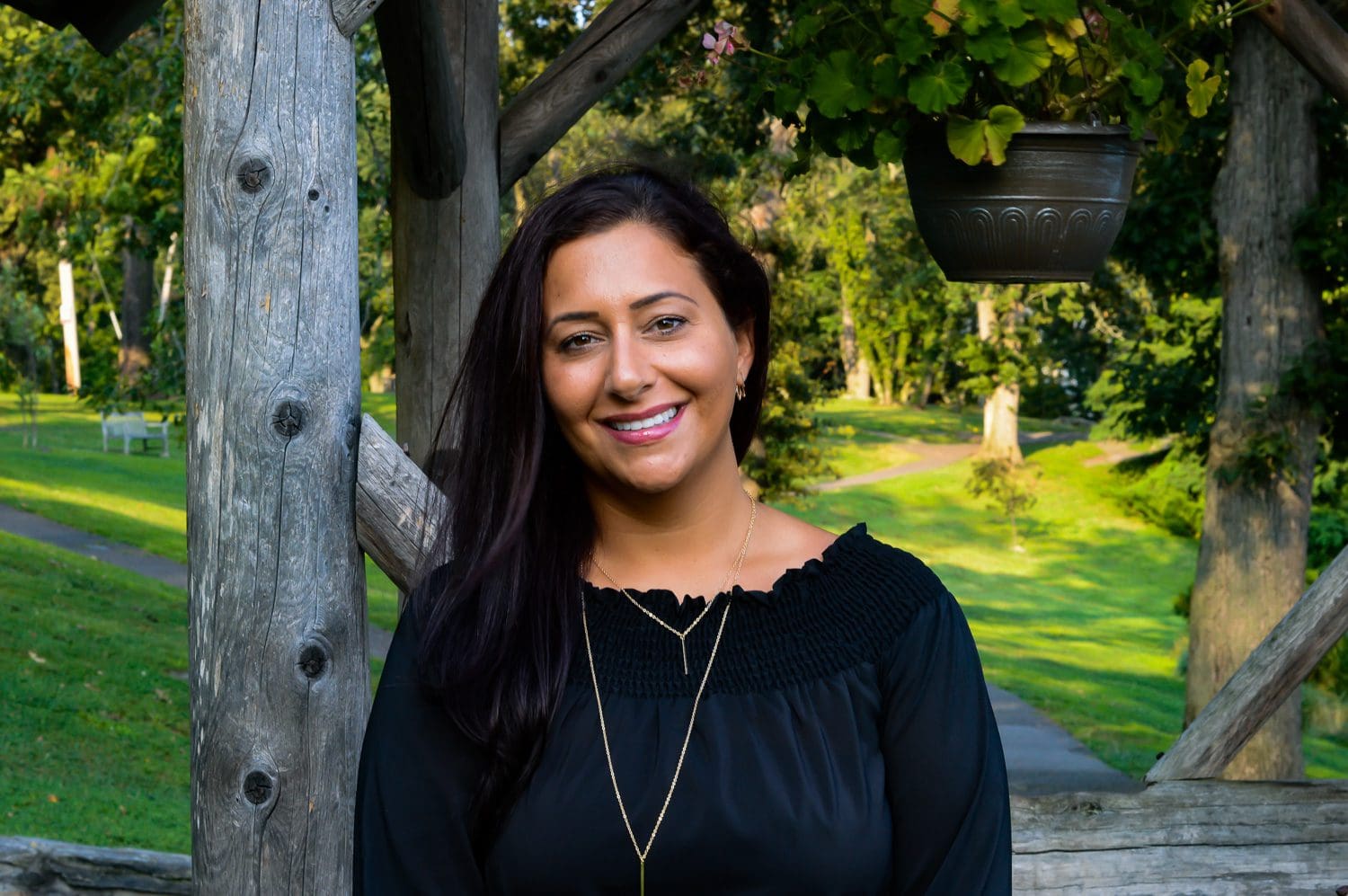 A woman standing in front of a tree smiling.