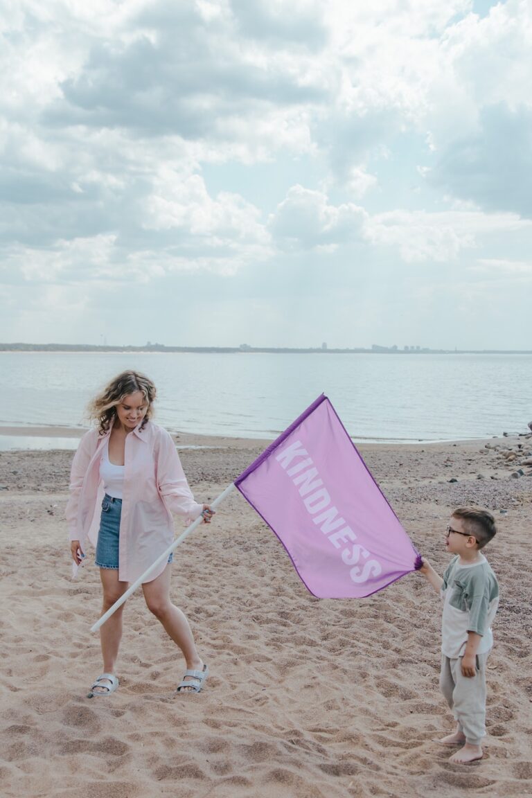 A woman and child flying a kite on the beach.